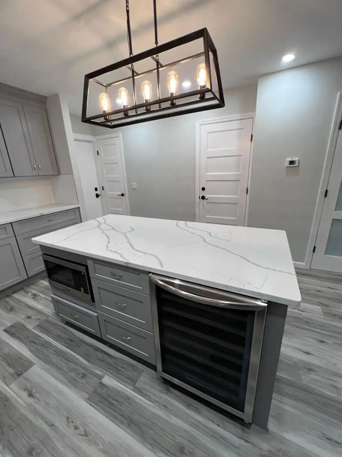 Contemporary kitchen island with marble surface and gray cabinetry.