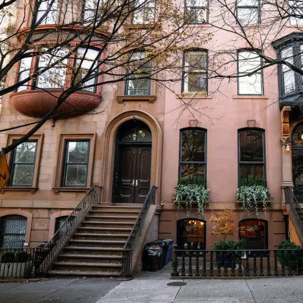 Brownstone townhouse with stairs and large windows in Brooklyn.
